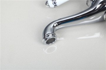 Elegante chroom kleurige wastafelkraan met witte(keramiek) elementen afgewerkt