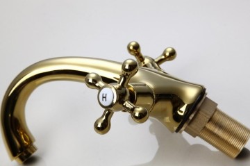 Elegante gouden wastafelkraan met witte elementen afgewerkt