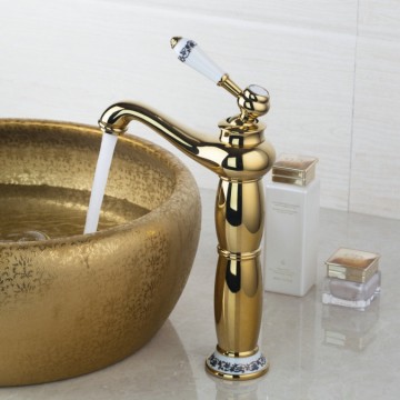 Nostalgische hoge goudkleurige wastafelkraan met witte elementen afgewerkt