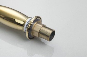 Nostalgische hoge goudkleurige wastafelkraan met witte elementen afgewerkt