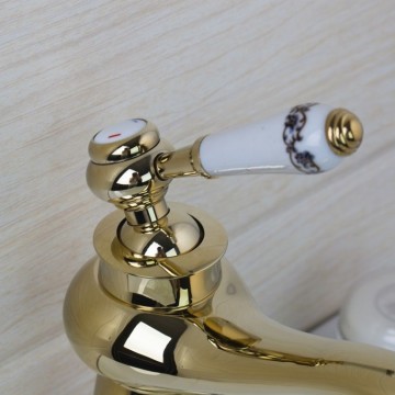 Elegante goudkleurige wastafelkraan met witte elementen afgewerkt