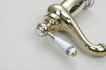 Elegante goudkleurige wastafelkraan met witte elementen afgewerkt