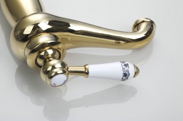 Nostalgische hoge goudkleurige wastafelkraan met witte elementen afgewerkt