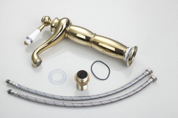 Nostalgische hoge goudkleurige wastafelkraan met witte elementen afgewerkt