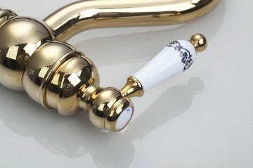 Nostalgische goudkleurige wastafelkraan met witte elementen afgewerkt draaibaar