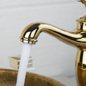 Nostalgische hoge goudkleurige wastafelkraan met witte elementen afgewerkt